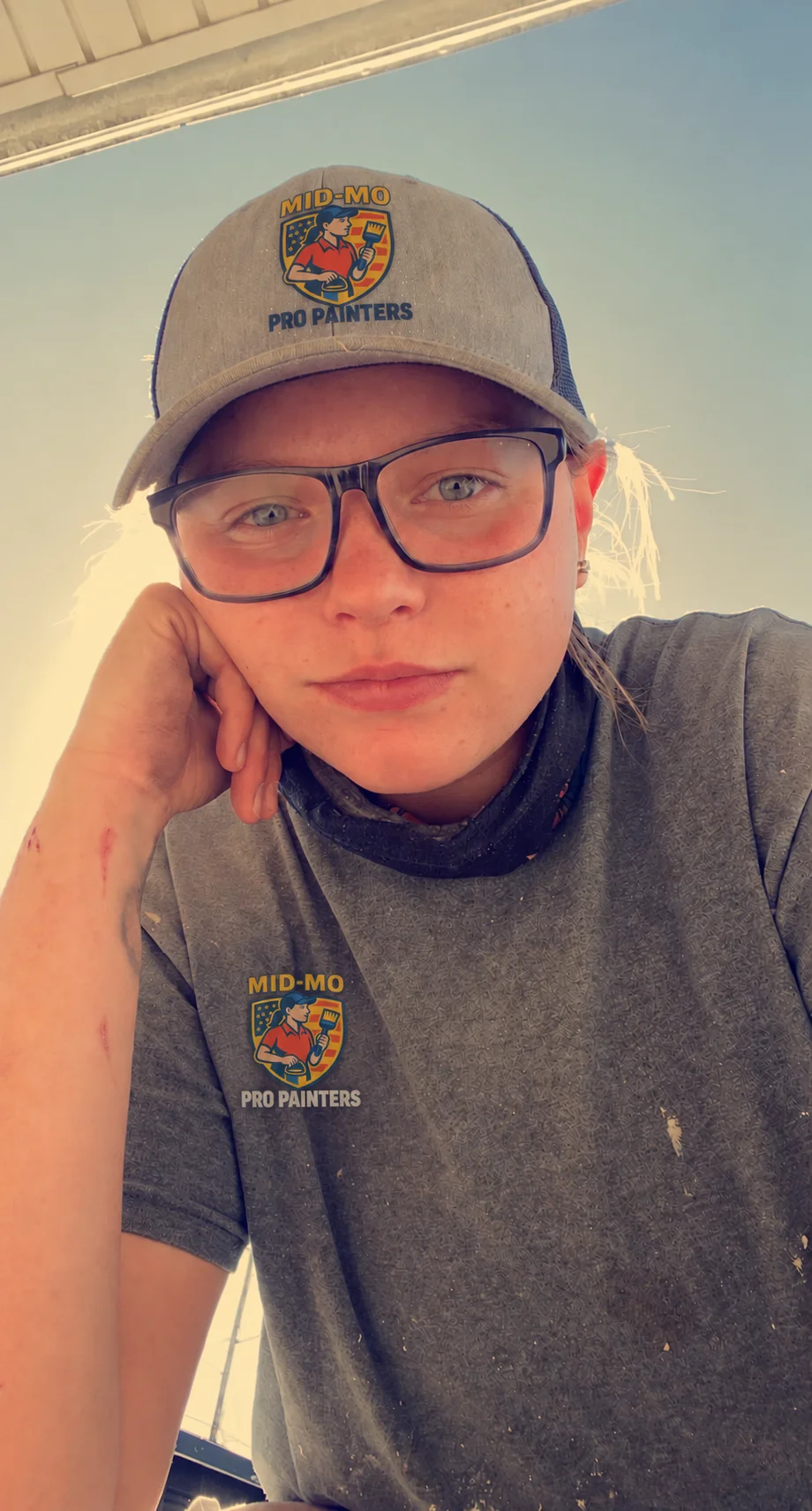 Anna wearing a cap and work shirt with the Mid Mo Pro Painters logo